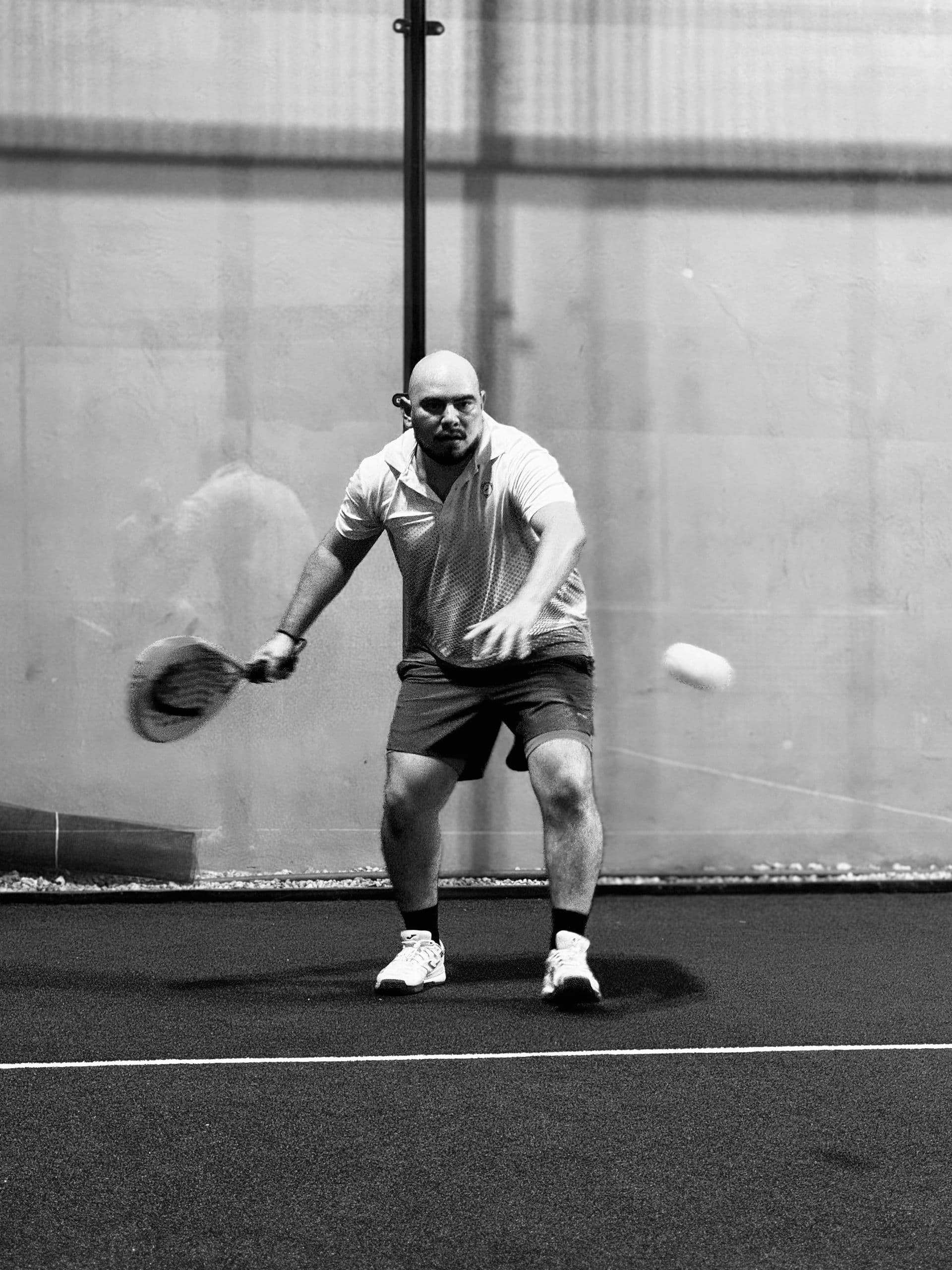Padel player mid-rally on an indoor court — illustrative photography, not a Courvia event