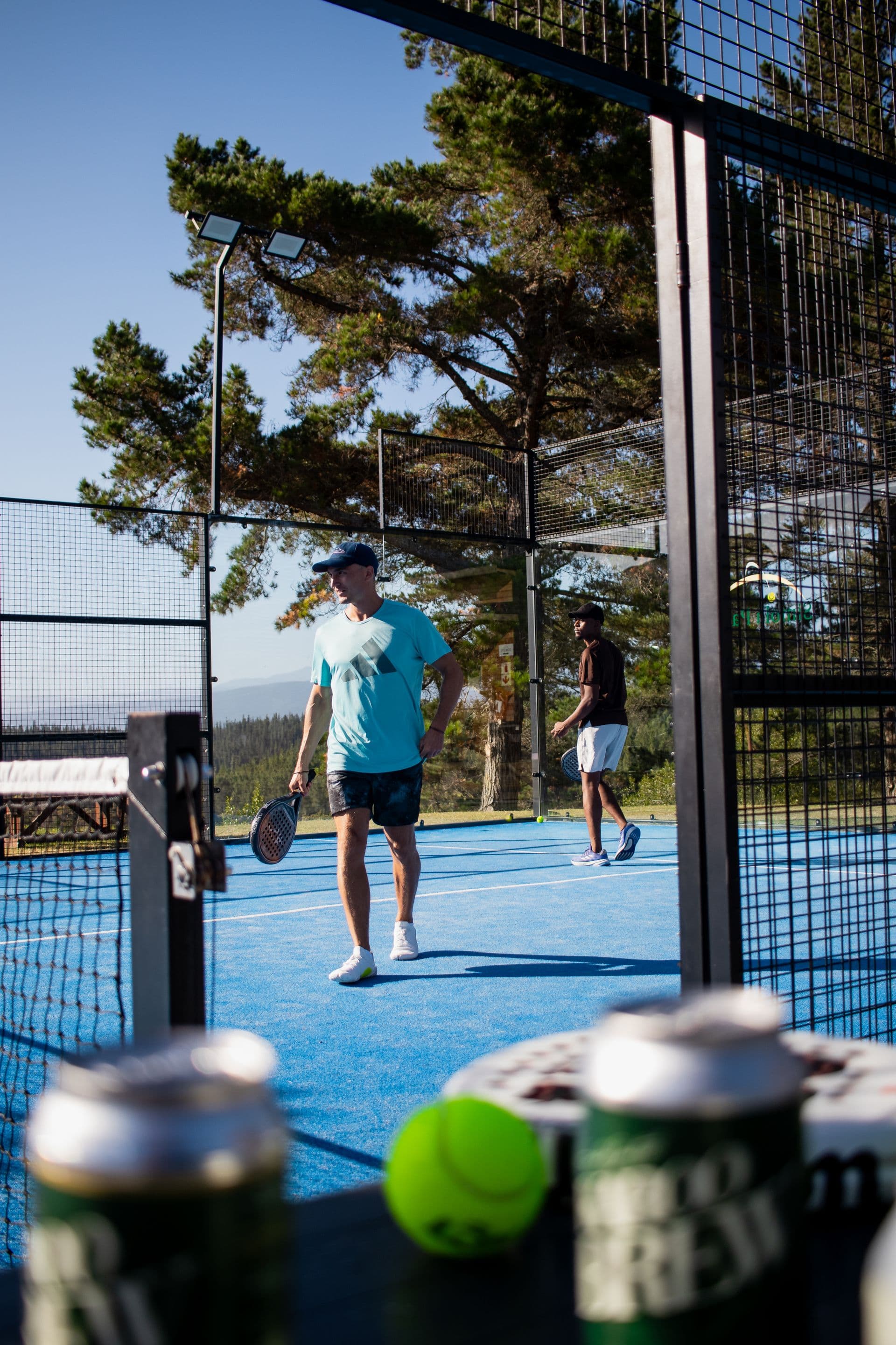 Two colleagues playing padel together on a sunny outdoor court — illustrative photography, not a Courvia event